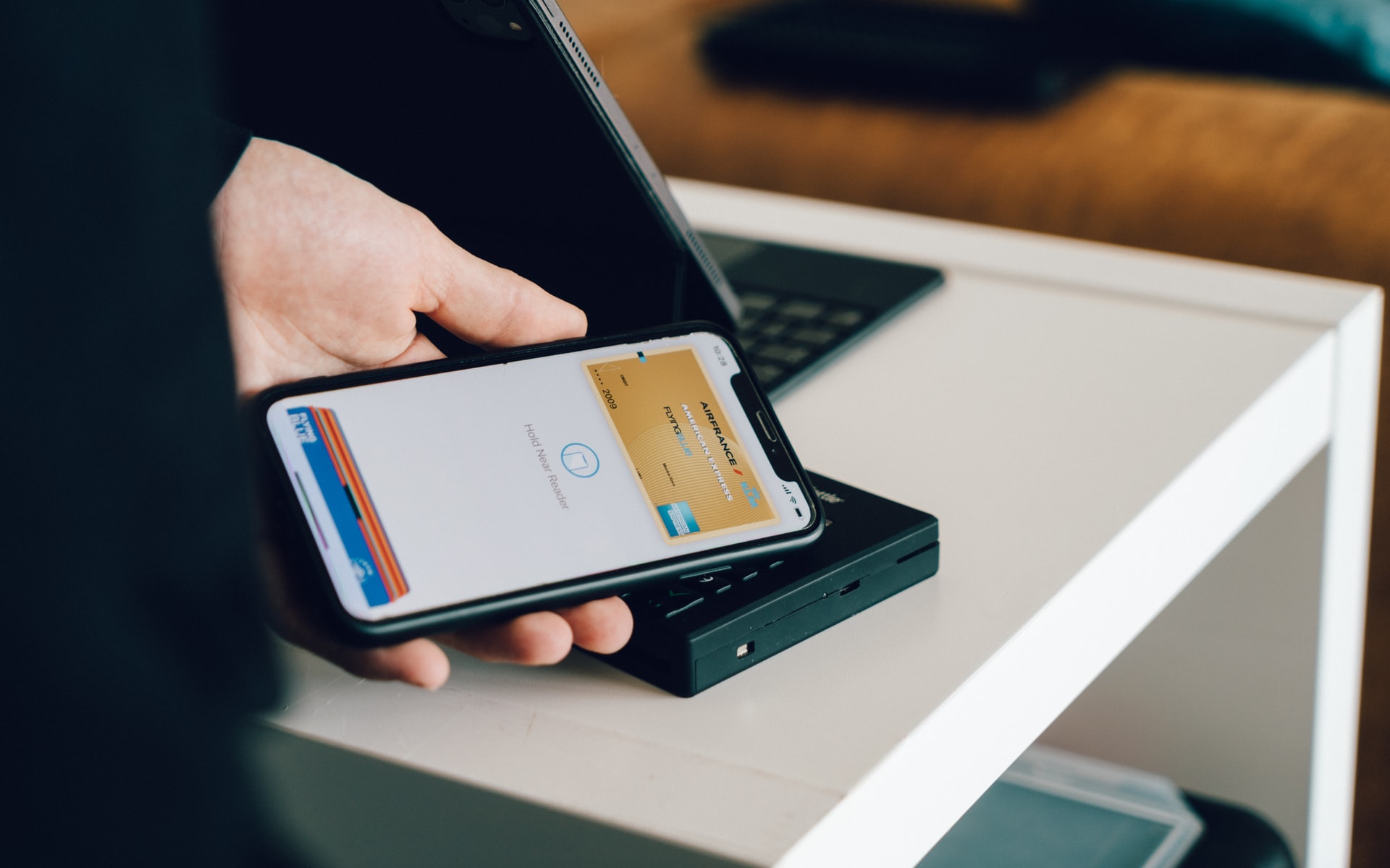 A man tapping his smartphone on a NFC terminal to make a mobile payment