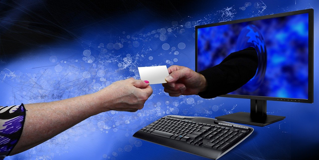 Two hands exchanging a white piece of paper through a computer