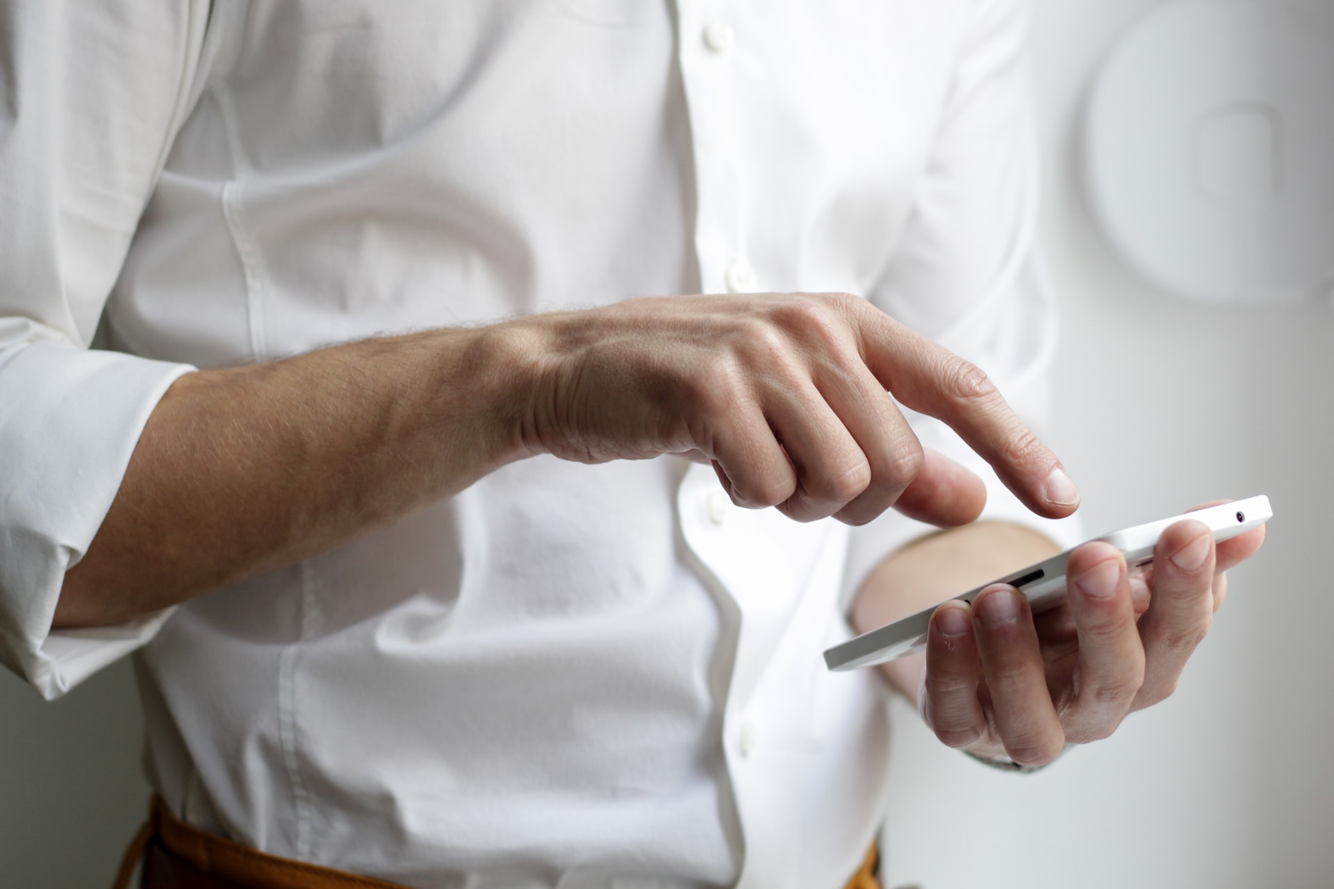 man in white dress shirt using smartphone