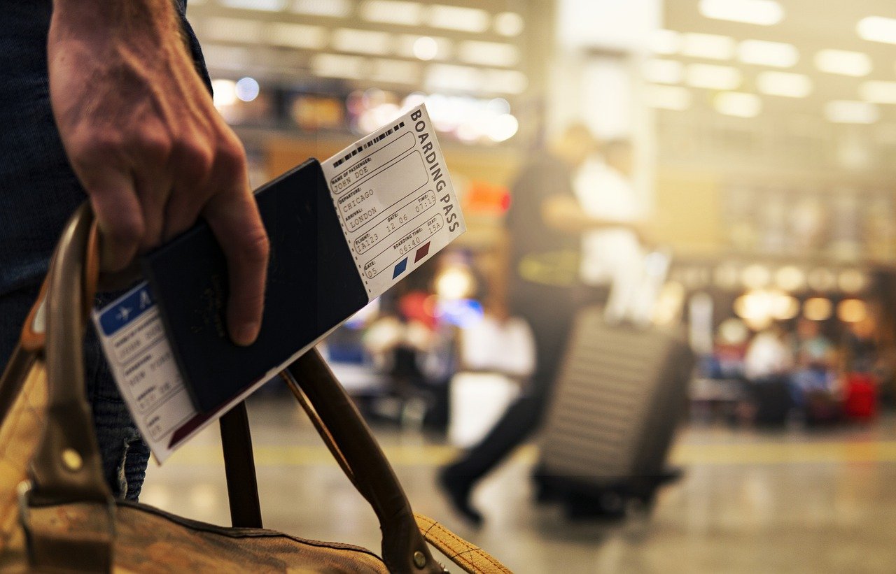 A male traveller in an airport with a boarding pass in his right hand
