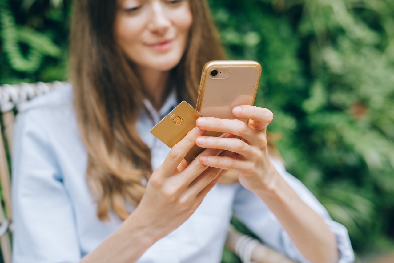 A happy young woman using a credit card to make a mobile payment