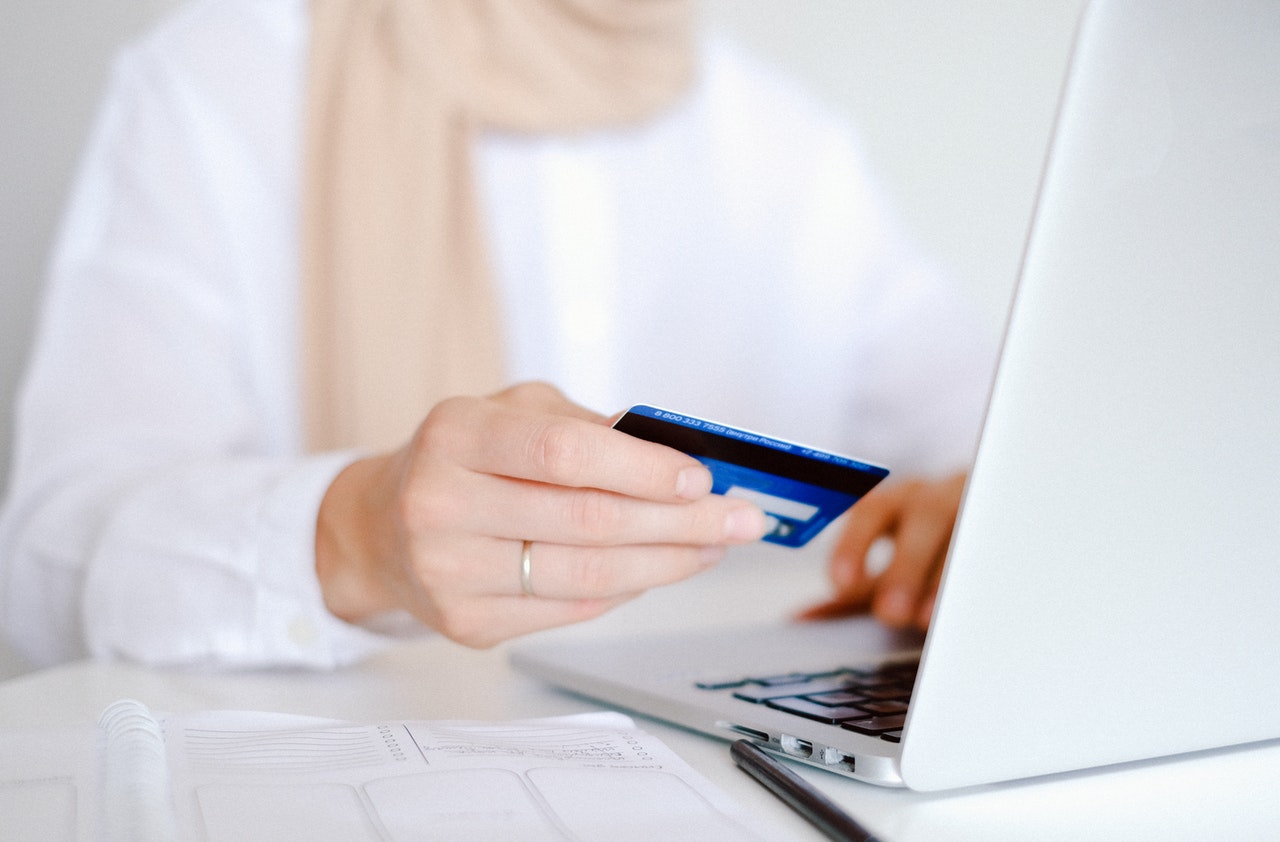 A person holding a credit card and using a laptop