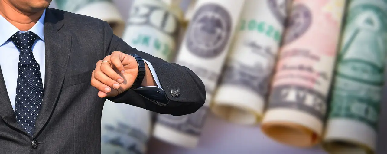 A businessman in front of rolled up dollar bills looking at his watch