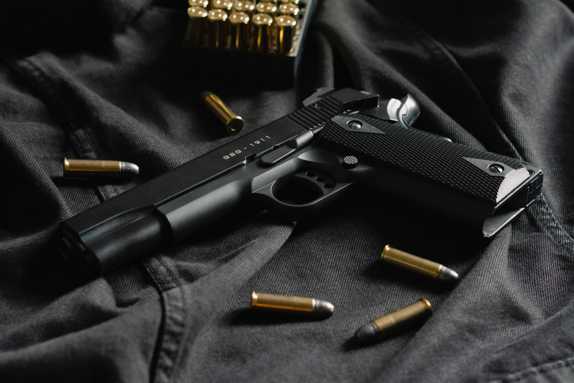 A gun and some bullets lying on a black pad.