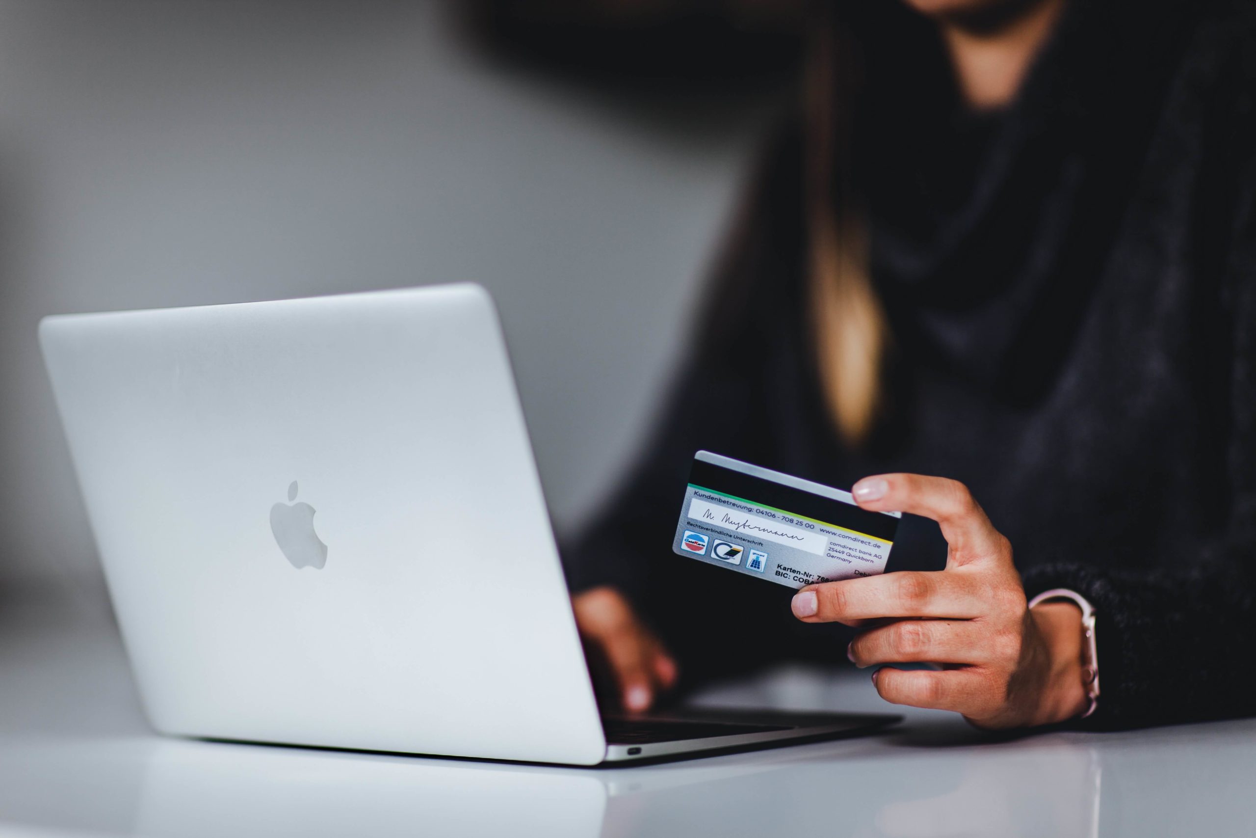 A woman holding a credit card and using a laptop